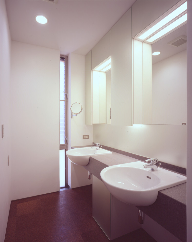 東京23区にある高級な広いモダンスタイルのおしゃれなトイレ・洗面所 (ガラス扉のキャビネット、白いキャビネット、白い壁、コルクフローリング、オーバーカウンターシンク、人工大理石カウンター、茶色い床) の写真