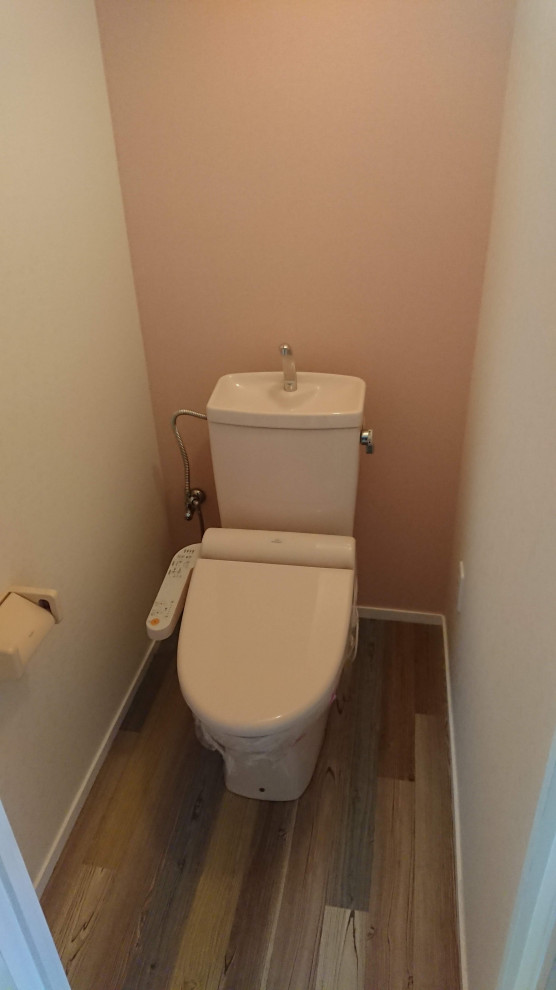 Inredning av ett klassiskt stort toalett, med en toalettstol med separat cisternkåpa, rosa kakel, beige väggar, plywoodgolv och flerfärgat golv