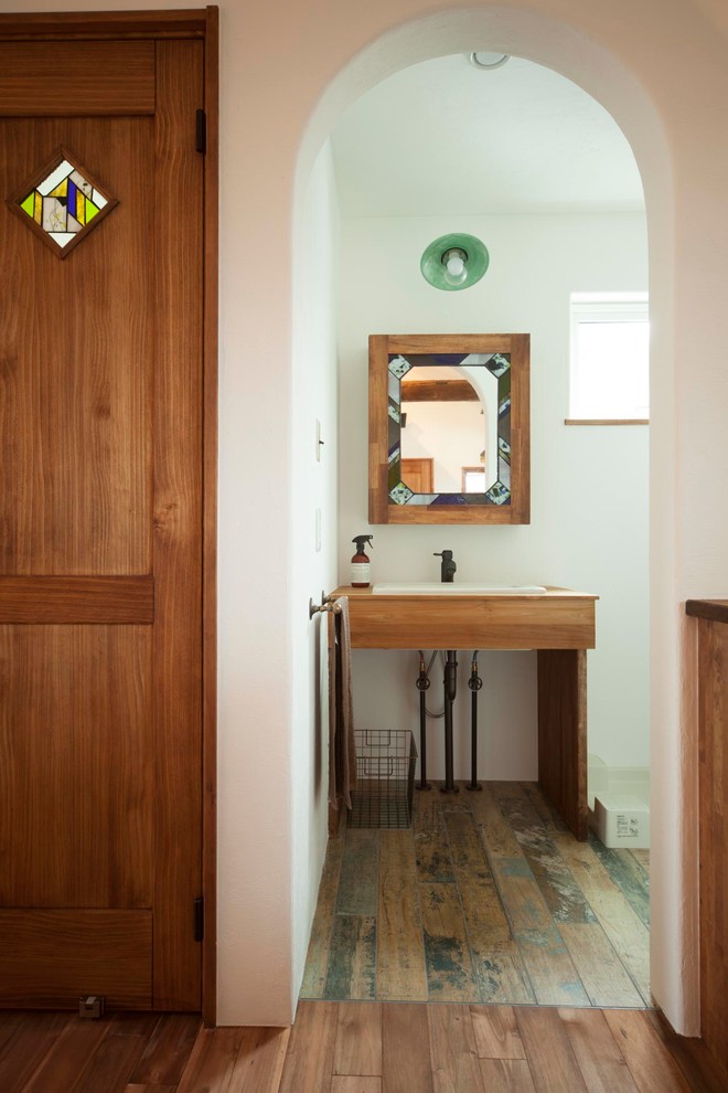 Example of a painted wood floor powder room design in Other with white walls and a drop-in sink