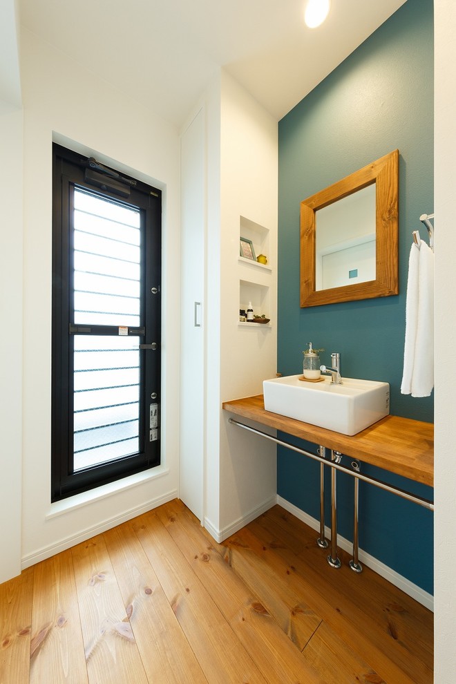 他の地域にある北欧スタイルのおしゃれなトイレ・洗面所 (青い壁、無垢フローリング、ベッセル式洗面器、木製洗面台、オレンジの床、ブラウンの洗面カウンター) の写真