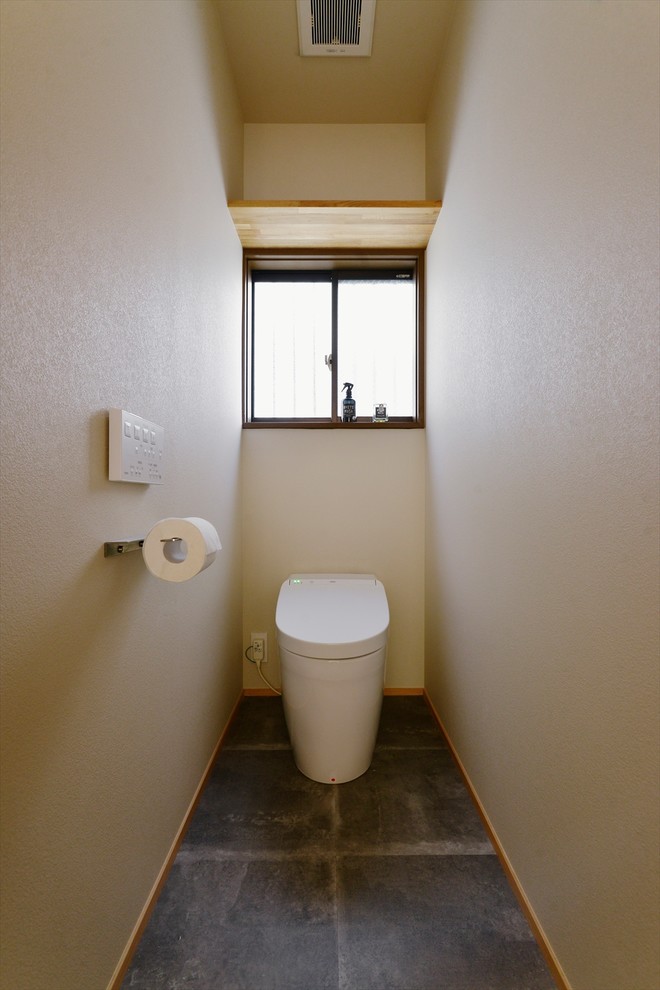 Foto på ett industriellt toalett, med vita väggar, betonggolv och grått golv