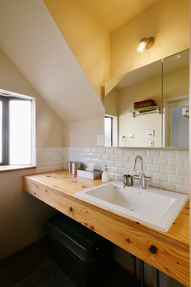 Industriell inredning av ett toalett, med beige väggar, ett nedsänkt handfat och träbänkskiva