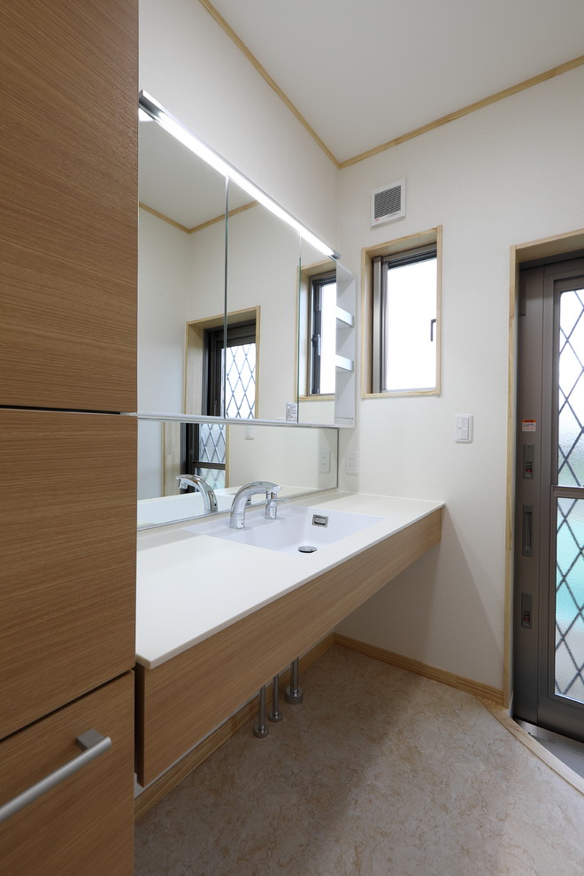 Photo of a large cloakroom in Other with freestanding cabinets, light wood cabinets, white walls, laminate floors, an integrated sink, solid surface worktops, beige floors and white worktops.