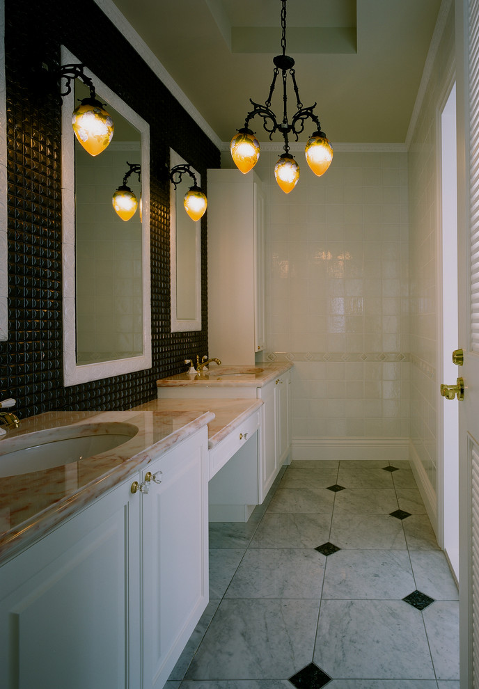Exemple d'un WC et toilettes victorien avec un placard avec porte à panneau surélevé, des portes de placard blanches, un mur blanc, un lavabo encastré, un carrelage blanc, un carrelage noir et un sol multicolore.