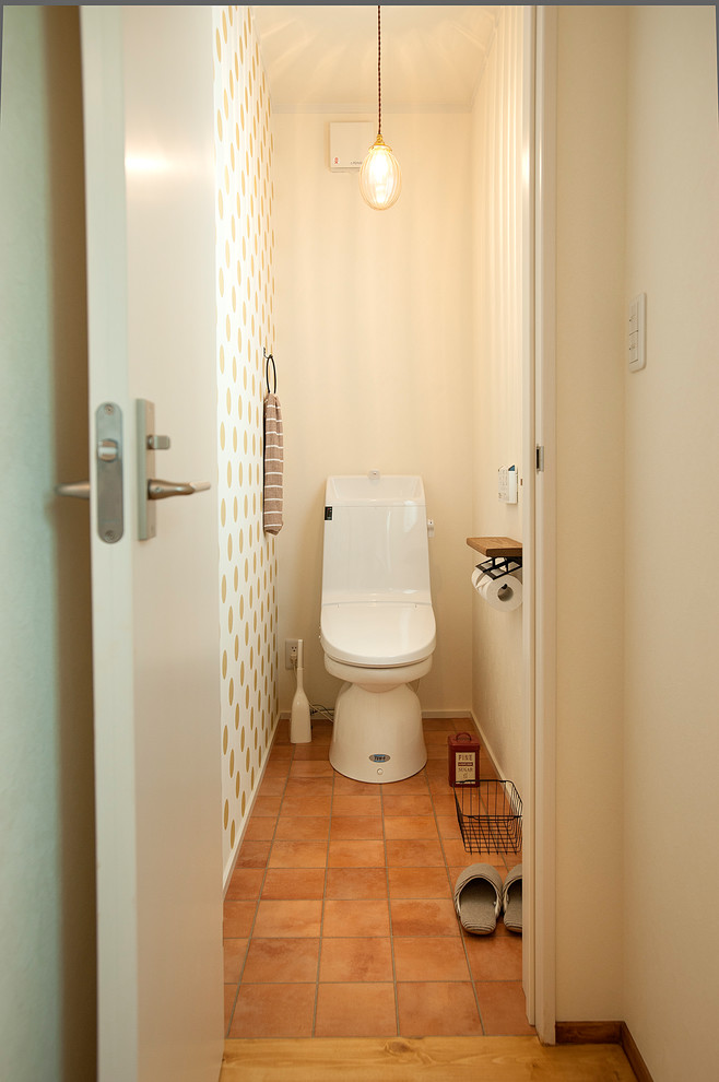 Idée de décoration pour un petit WC et toilettes asiatique avec un mur multicolore, tomettes au sol et un sol marron.