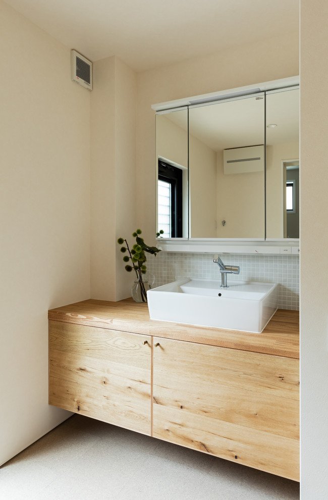 Idee per un bagno di servizio etnico con ante lisce, ante marroni, pareti bianche, lavabo a bacinella, top in legno, pavimento beige e top marrone