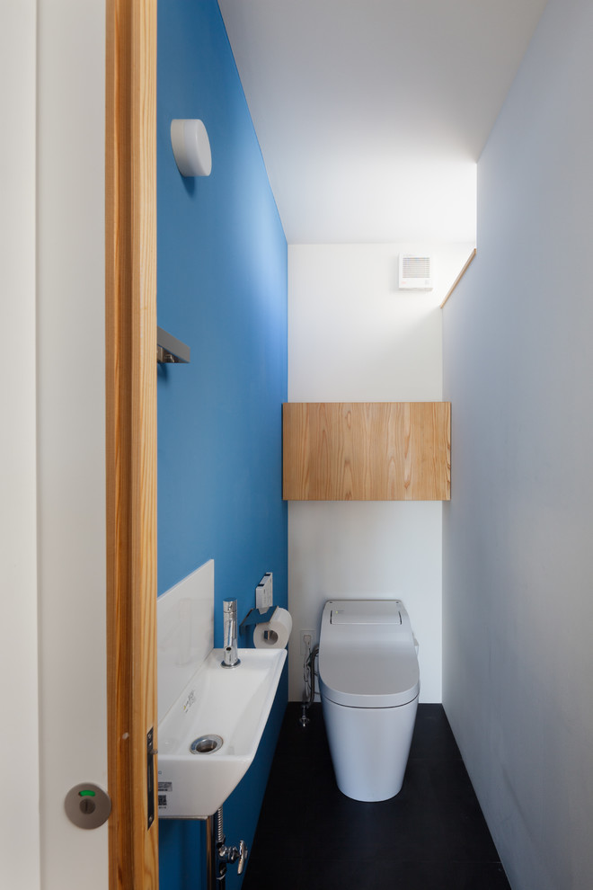Kleine Moderne Gästetoilette mit flächenbündigen Schrankfronten, hellbraunen Holzschränken, Toilette mit Aufsatzspülkasten, Linoleum und schwarzem Boden in Yokohama