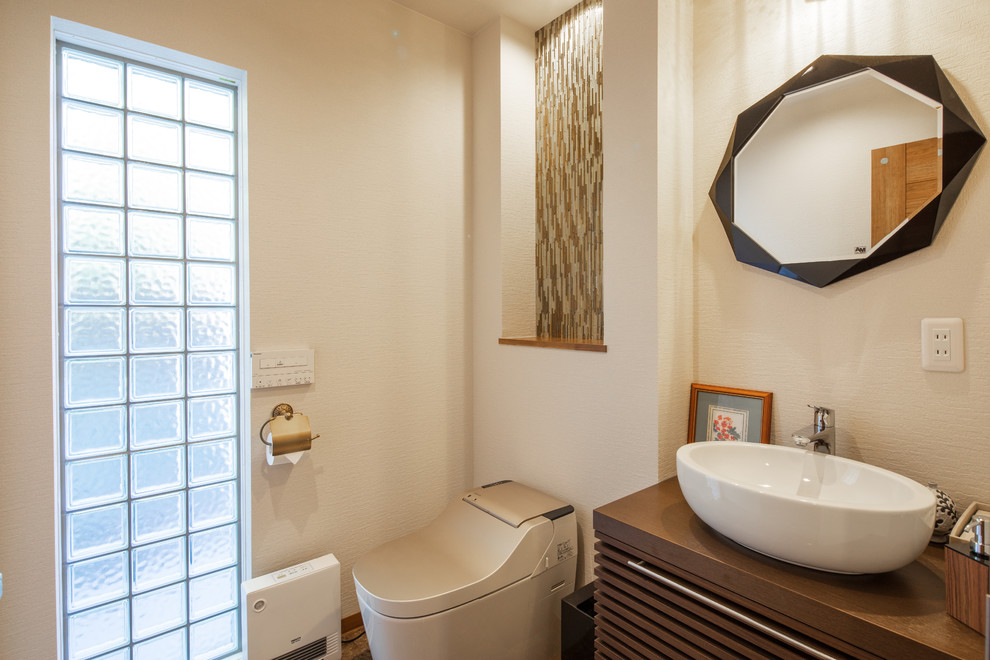 他の地域にあるアジアンスタイルのおしゃれなトイレ・洗面所 (中間色木目調キャビネット、一体型トイレ	、白い壁、ベッセル式洗面器、木製洗面台) の写真