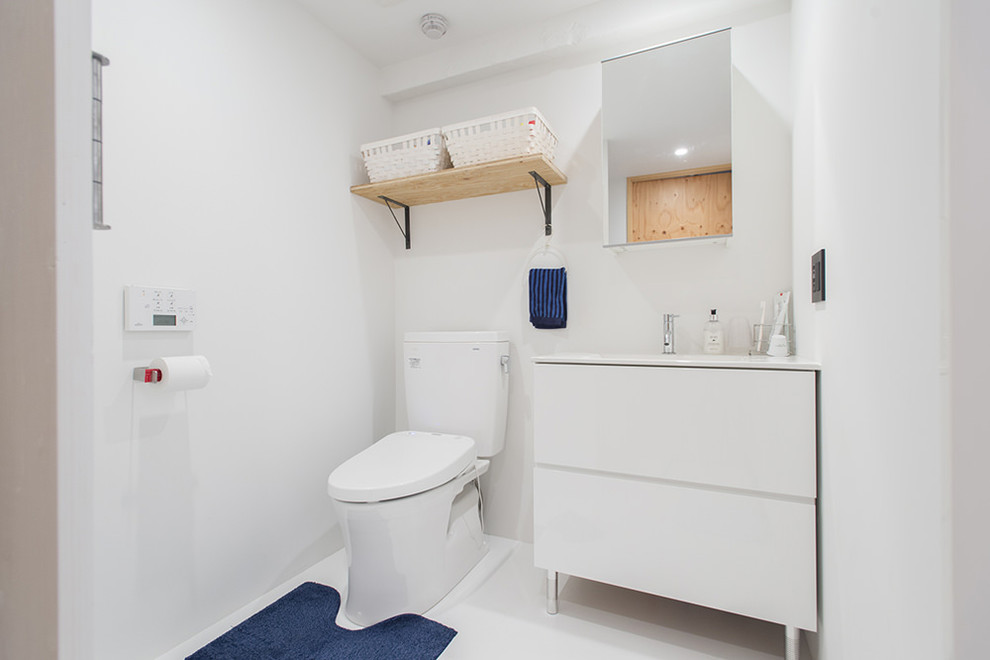 東京23区にあるモダンスタイルのおしゃれなトイレ・洗面所 (フラットパネル扉のキャビネット、白いキャビネット、白い壁、一体型シンク、白い床) の写真