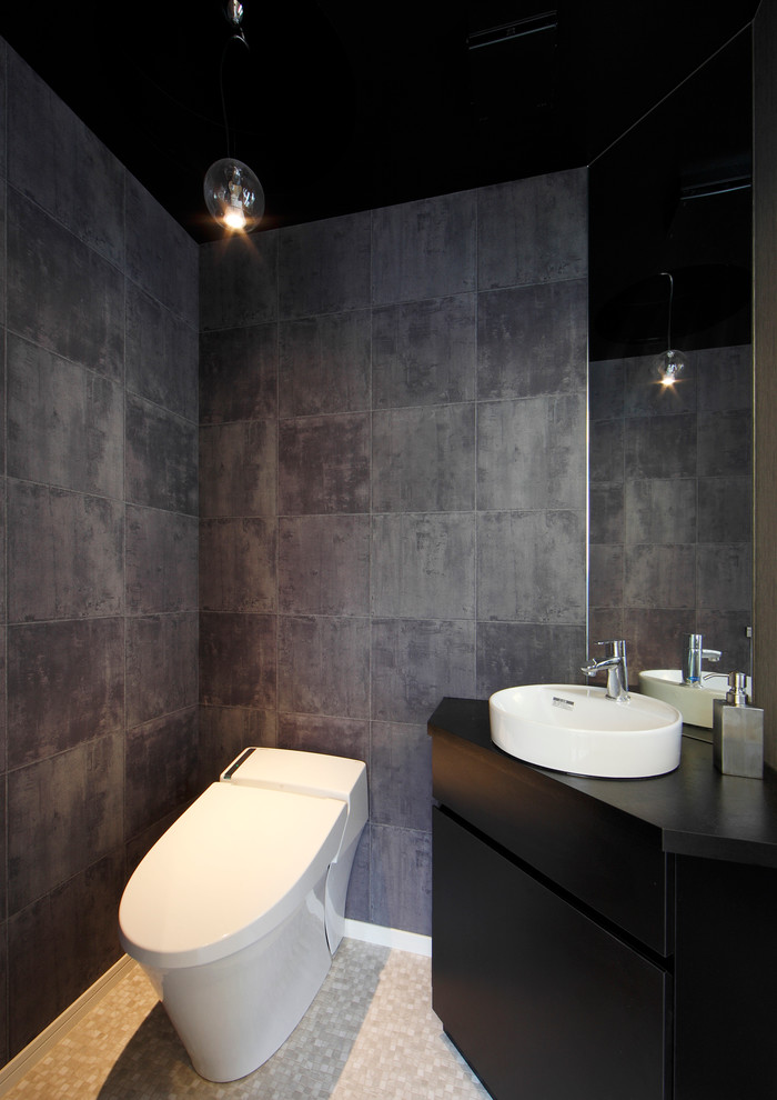 Inspiration för ett mellanstort funkis toalett, med släta luckor, svarta skåp, en toalettstol med hel cisternkåpa, grå väggar, ett fristående handfat, beiget golv och grå kakel