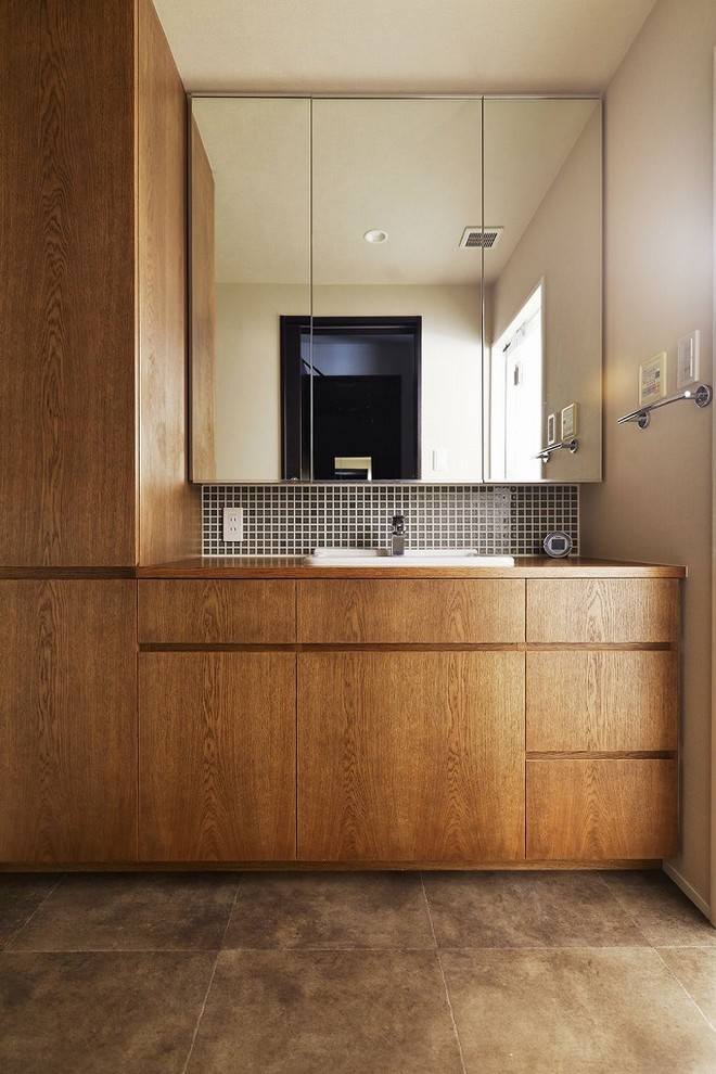 アジアンスタイルのおしゃれなトイレ・洗面所 (茶色いキャビネット、白い壁、オーバーカウンターシンク、木製洗面台、茶色い床、ブラウンの洗面カウンター) の写真