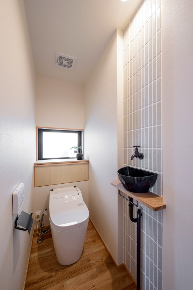 Идея дизайна: туалет в восточном стиле с белыми стенами, паркетным полом среднего тона, настольной раковиной и коричневым полом