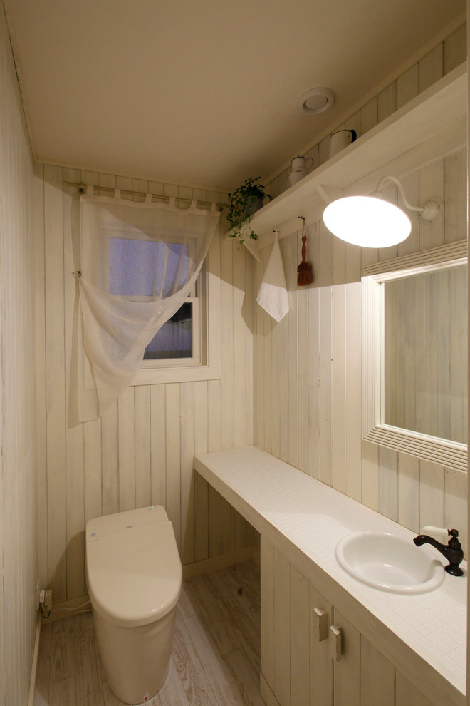 他の地域にあるカントリー風のおしゃれなトイレ・洗面所 (白いキャビネット、白い壁、塗装フローリング、オーバーカウンターシンク、白い床) の写真