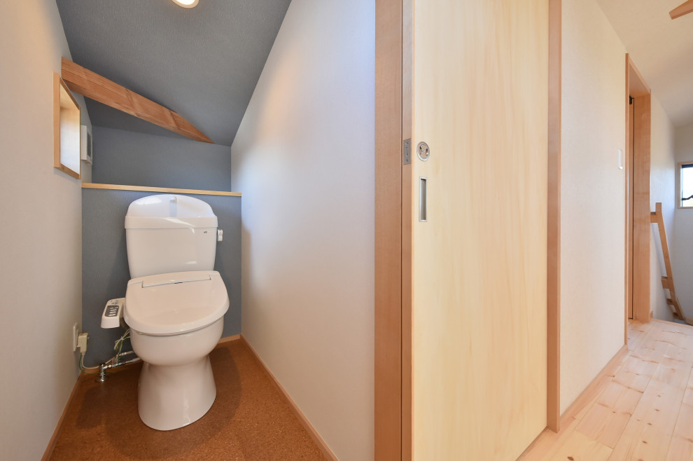 Пример оригинального дизайна: туалет с белыми фасадами, унитазом-моноблоком, зеленой плиткой, пробковым полом, коричневым полом, потолком с обоями и обоями на стенах