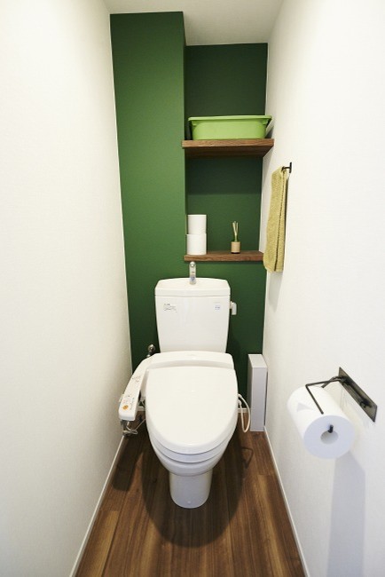 他の地域にある中くらいなコンテンポラリースタイルのおしゃれなトイレ・洗面所 (白い壁、合板フローリング、茶色い床、オープンシェルフ、緑のキャビネット、一体型トイレ	、白いタイル、モザイクタイル、アンダーカウンター洗面器、白い洗面カウンター) の写真