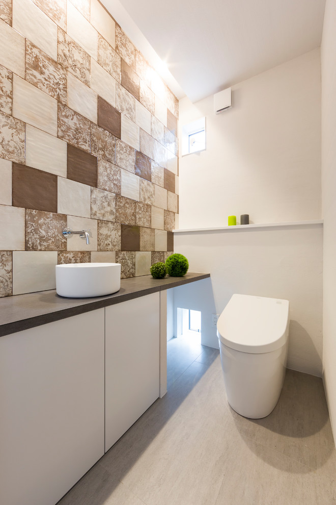 Exemple d'un WC et toilettes asiatique avec un carrelage marron, un mur multicolore et un sol gris.