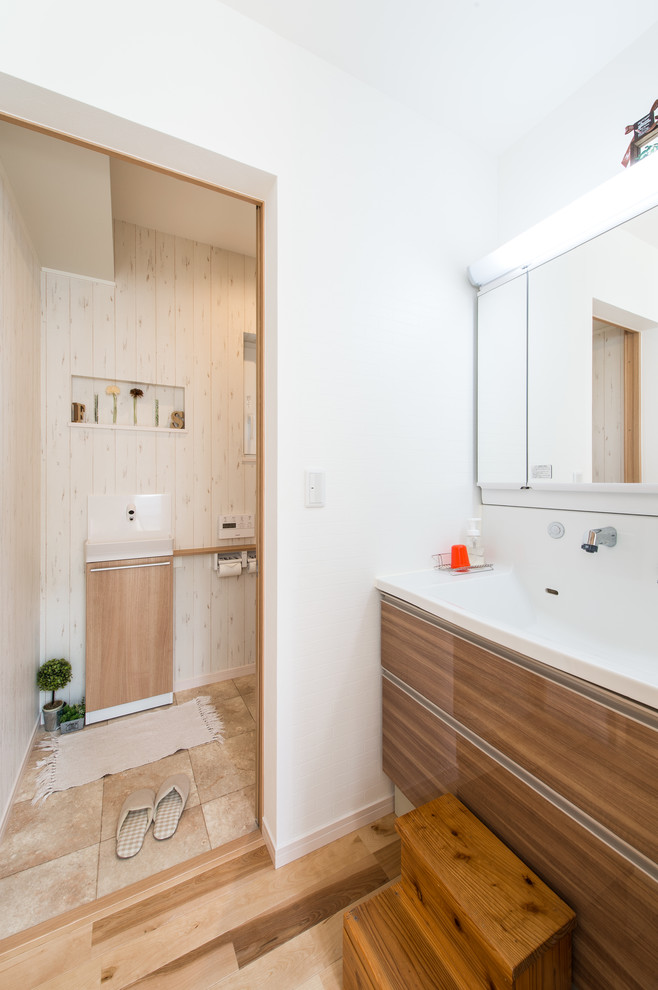 Idéer för att renovera ett minimalistiskt toalett, med släta luckor, skåp i mellenmörkt trä, vita väggar, ett integrerad handfat och brunt golv