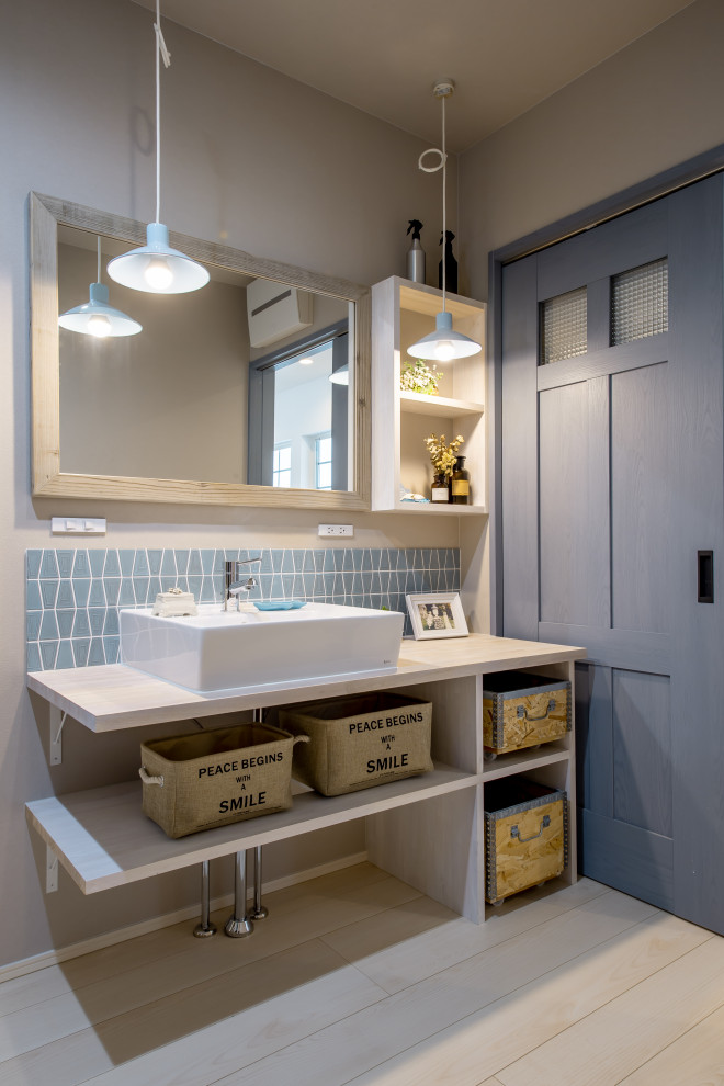 This is an example of a medium sized cloakroom in Other with open cabinets, green tiles, a vessel sink, white worktops, a built in vanity unit, a wallpapered ceiling and wallpapered walls.