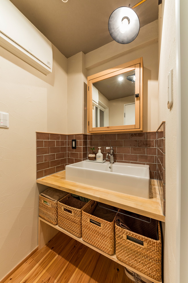 Idéer för att renovera ett orientaliskt brun brunt toalett, med öppna hyllor, brun kakel, vita väggar, mellanmörkt trägolv, ett fristående handfat, träbänkskiva och brunt golv