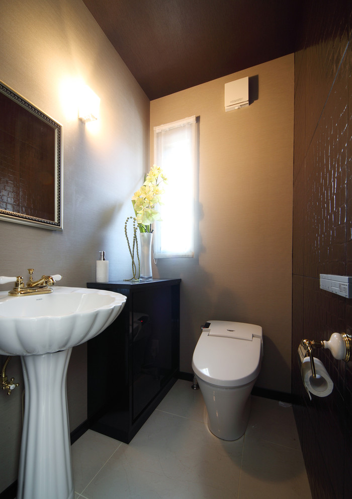 Aménagement d'un WC et toilettes classique de taille moyenne avec un placard en trompe-l'oeil, des portes de placard noires, WC à poser, un carrelage marron, des carreaux de céramique, un mur beige, un sol en carrelage de céramique, une vasque et un sol gris.