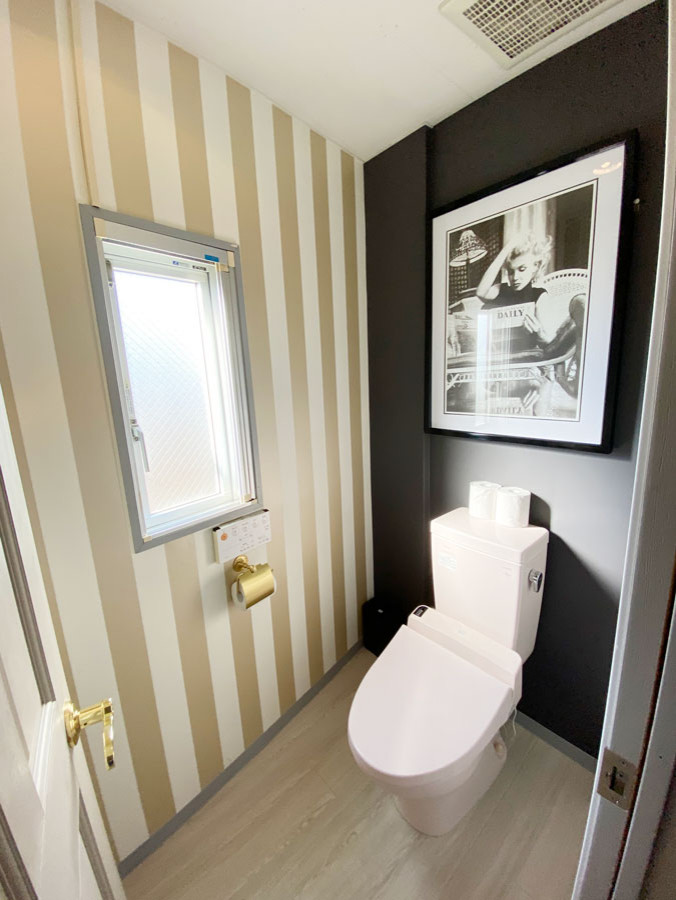 Réalisation d'un petit WC et toilettes style shabby chic avec meuble-lavabo sur pied, un placard à porte affleurante, des portes de placard blanches, des carreaux de porcelaine, un sol beige, un plan de toilette blanc et un mur noir.