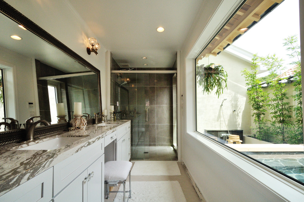 広いアジアンスタイルのおしゃれなトイレ・洗面所 (グレーの壁、磁器タイルの床、白いキャビネット、グレーのタイル、ベージュの床、グレーの洗面カウンター) の写真