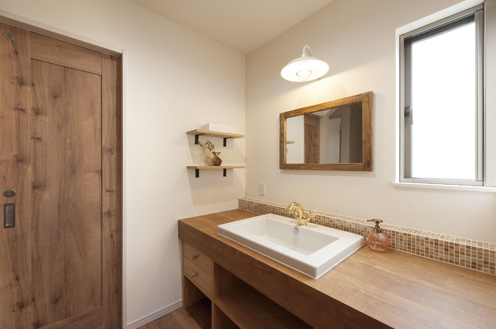 Asiatische Gästetoilette mit weißer Wandfarbe, braunem Holzboden, Einbauwaschbecken, Waschtisch aus Holz, braunem Boden und brauner Waschtischplatte in Osaka
