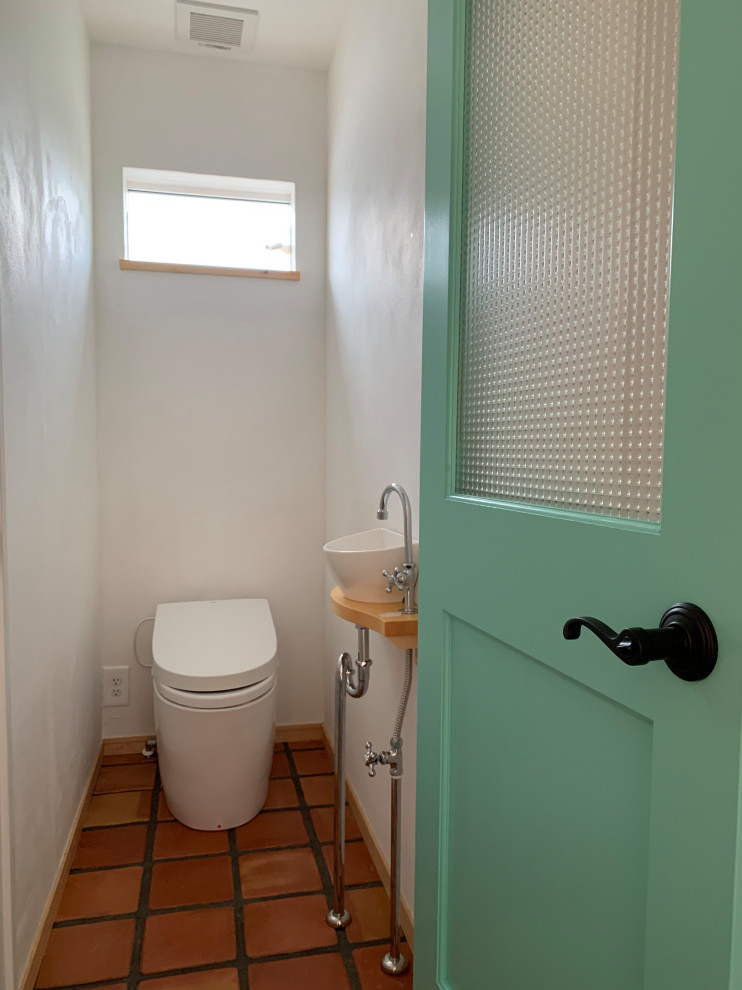 Design ideas for a medium sized cloakroom in Other with light wood cabinets, a one-piece toilet, white tiles, white walls, terracotta flooring, orange floors, beige worktops and a built in vanity unit.