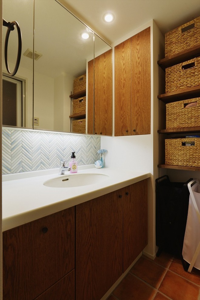 Moderne Gästetoilette mit offenen Schränken, hellbraunen Holzschränken, weißer Wandfarbe, Terrakottaboden, integriertem Waschbecken und orangem Boden