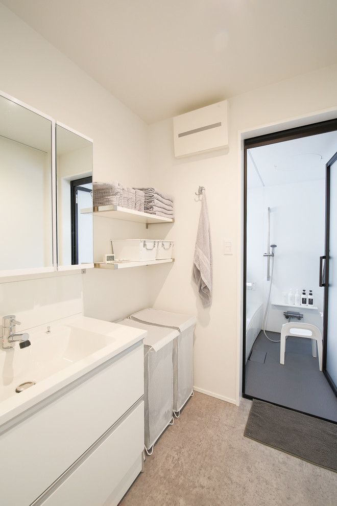 他の地域にあるモダンスタイルのおしゃれなトイレ・洗面所 (フラットパネル扉のキャビネット、白いキャビネット、白い壁、一体型シンク、グレーの床) の写真