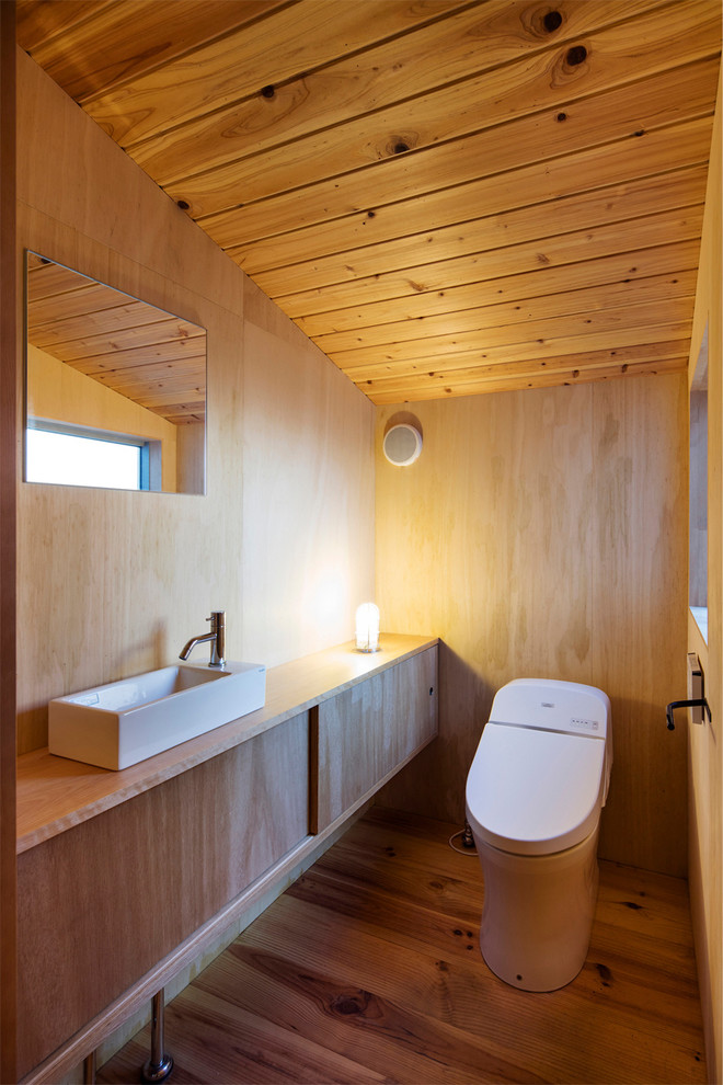 Inspiration för ett industriellt toalett, med släta luckor, skåp i mellenmörkt trä, bruna väggar, mellanmörkt trägolv, ett fristående handfat, träbänkskiva och brunt golv