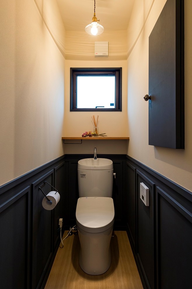 Inspiration pour un WC et toilettes urbain avec un placard à porte plane, des portes de placard noires, un mur blanc, un sol en marbre et un sol marron.