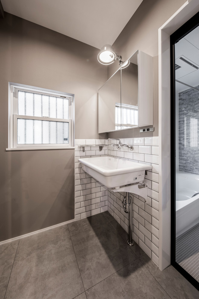 東京都下にあるインダストリアルスタイルのおしゃれなトイレ・洗面所 (グレーの壁、コンクリートの床、ベッセル式洗面器、グレーの床) の写真