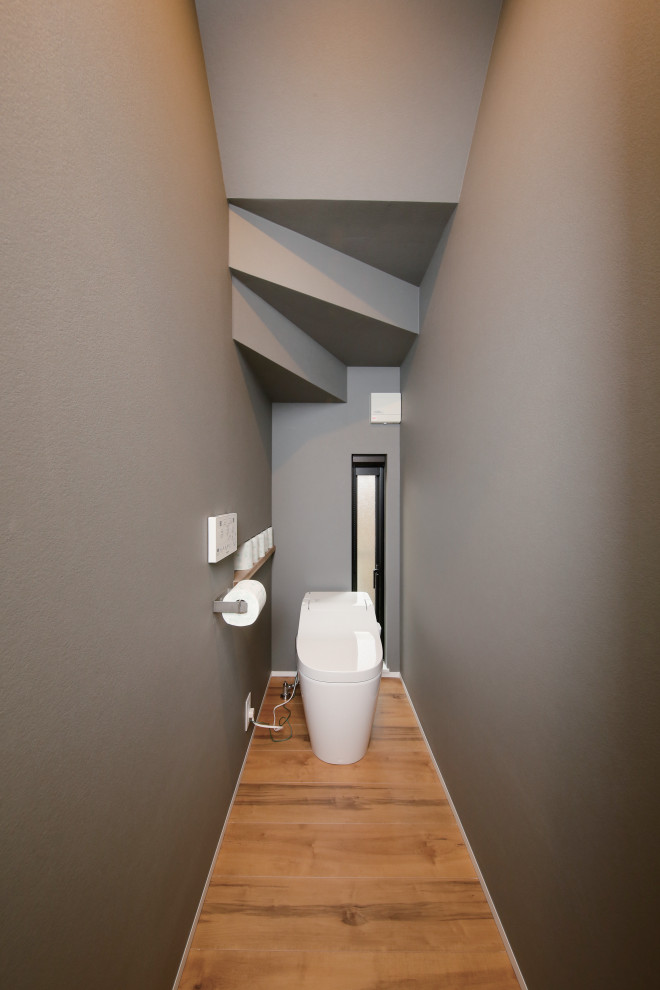 Idées déco pour un WC et toilettes industriel de taille moyenne avec WC séparés, un mur gris, parquet foncé, un sol marron, un plafond en papier peint et du papier peint.
