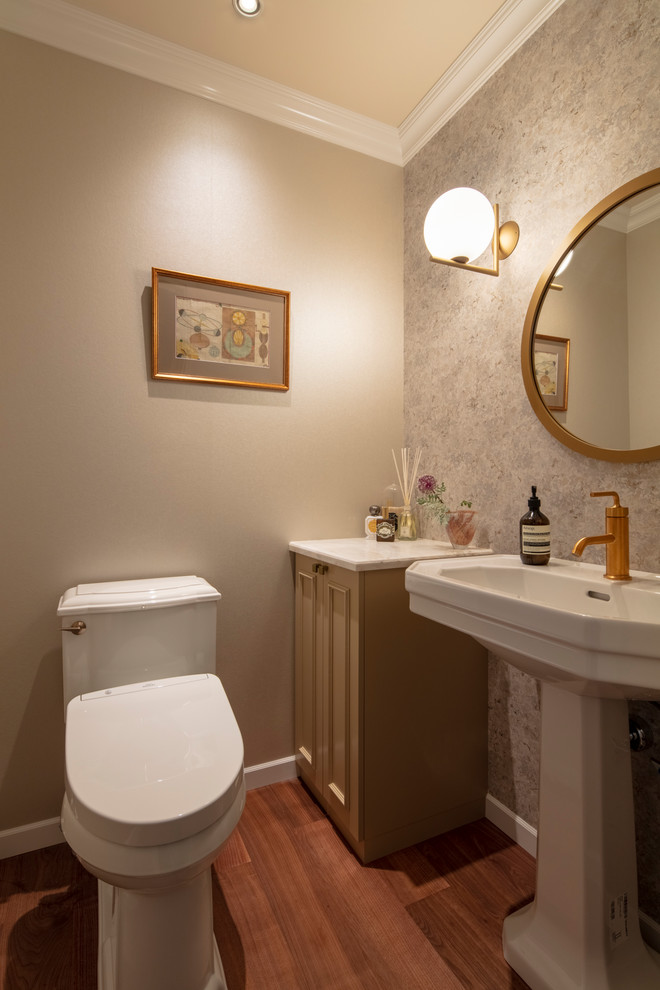 Aménagement d'un WC et toilettes victorien avec un placard avec porte à panneau encastré, des portes de placard marrons, un mur multicolore, un sol en bois brun, un plan vasque et un sol marron.