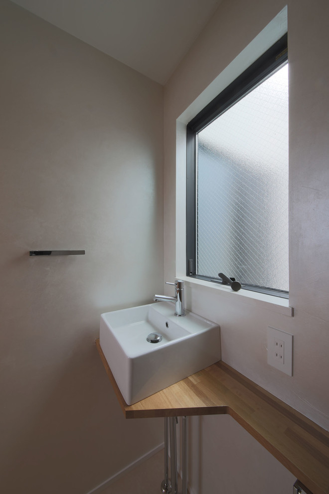 Kleine Moderne Gästetoilette mit beiger Wandfarbe, Sperrholzboden, Aufsatzwaschbecken, Waschtisch aus Holz, braunem Boden und brauner Waschtischplatte in Tokio