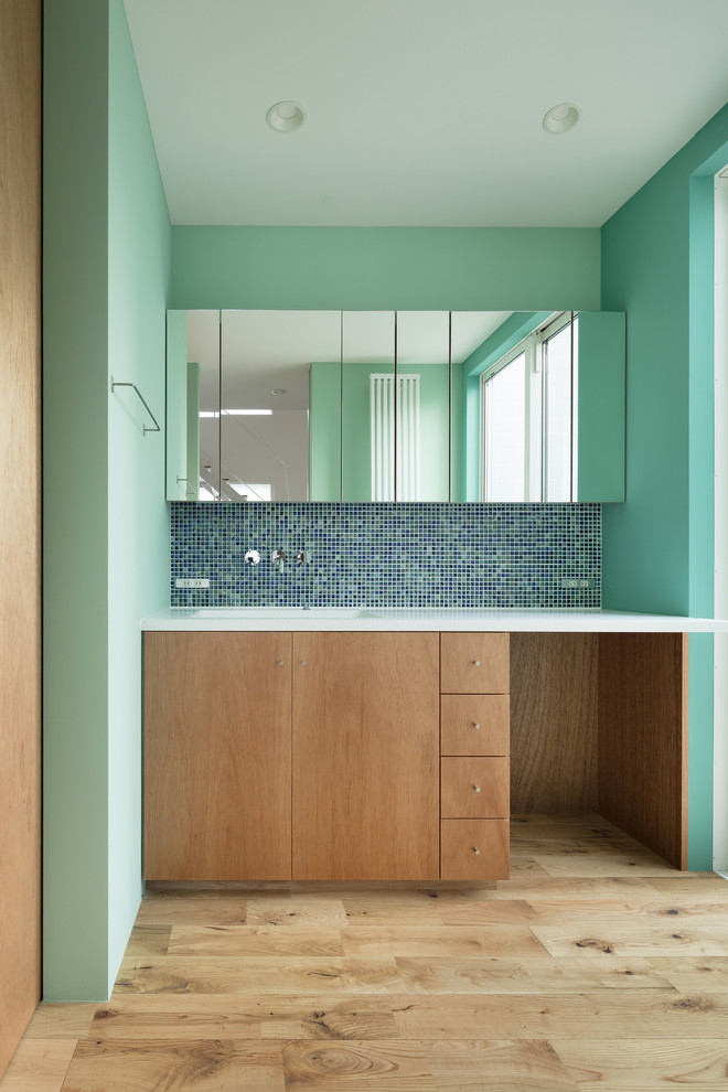 Inredning av ett modernt mellanstort toalett, med släta luckor, skåp i mellenmörkt trä, grön kakel, mosaik, gröna väggar, mellanmörkt trägolv, ett undermonterad handfat, bänkskiva i akrylsten och beiget golv