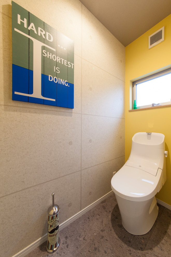 Réalisation d'un WC et toilettes urbain avec un mur jaune et un sol gris.
