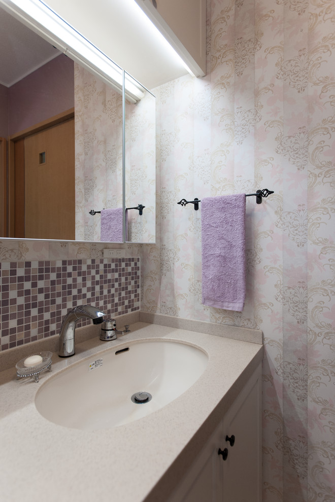 Réalisation d'un petit WC et toilettes style shabby chic avec un placard en trompe-l'oeil, des portes de placard blanches, un carrelage rose, un carrelage en pâte de verre, un mur rose, un sol en vinyl, un lavabo encastré, un plan de toilette en surface solide, un sol beige, un plan de toilette beige, un plafond en papier peint et du papier peint.