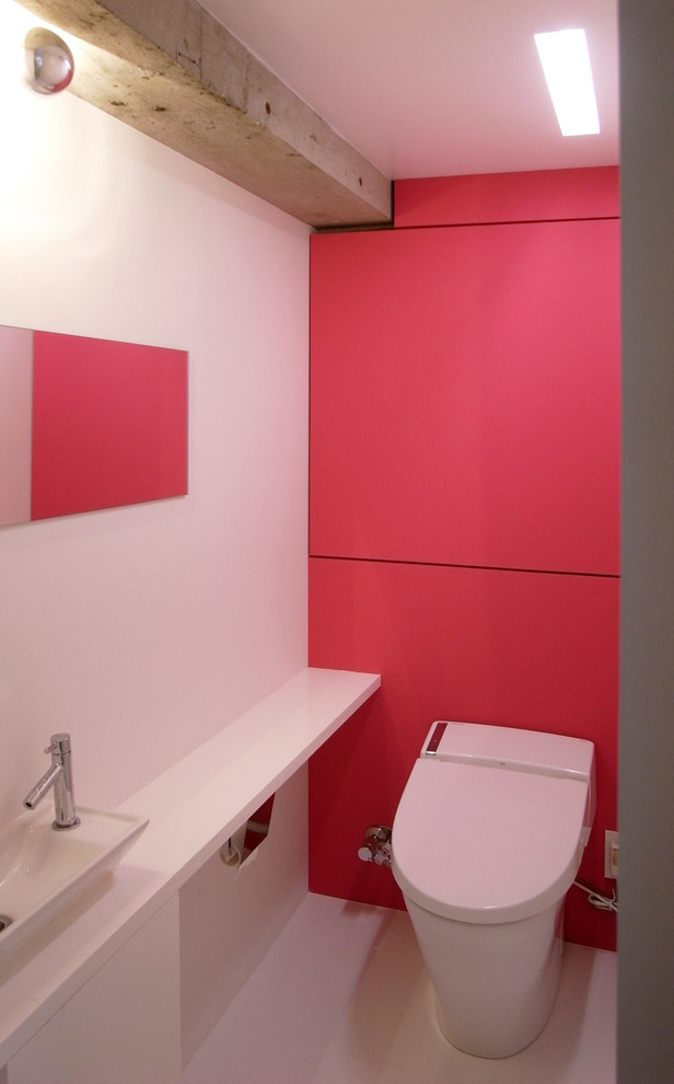 Moderne Gästetoilette mit Kassettenfronten, Toilette mit Aufsatzspülkasten, rosa Fliesen, rosa Wandfarbe, Vinylboden, Waschtisch aus Holz, weißem Boden und weißer Waschtischplatte in Tokio