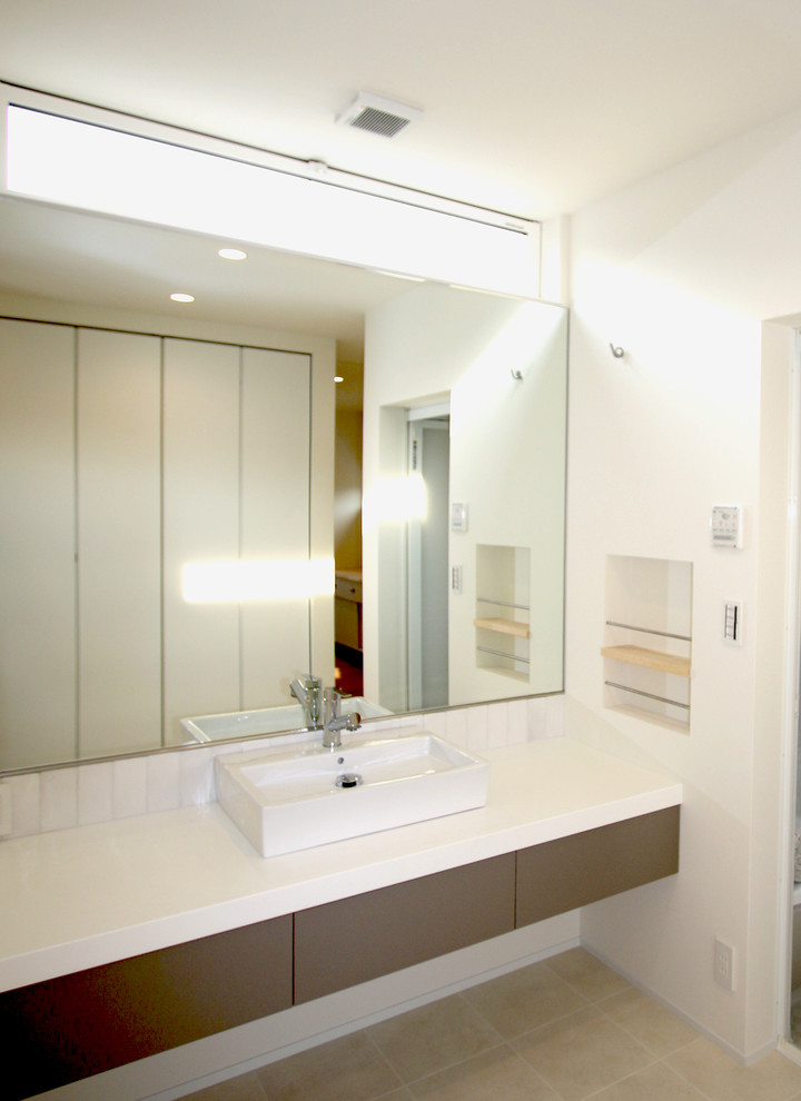 На фото: туалет в стиле модернизм с плоскими фасадами, серыми фасадами, белой плиткой, керамогранитной плиткой, белыми стенами, полом из ламината, настольной раковиной, столешницей из ламината и бежевым полом с