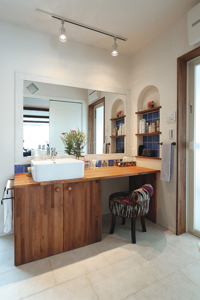 Idée de décoration pour un WC et toilettes champêtre en bois brun avec un placard à porte plane, un mur blanc, une vasque, un plan de toilette en bois et un sol beige.