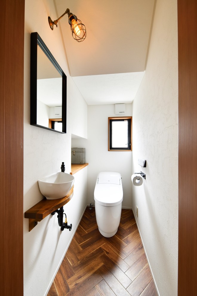 Inspiration for a small world-inspired cloakroom in Other with white walls, dark hardwood flooring, a vessel sink and brown floors.