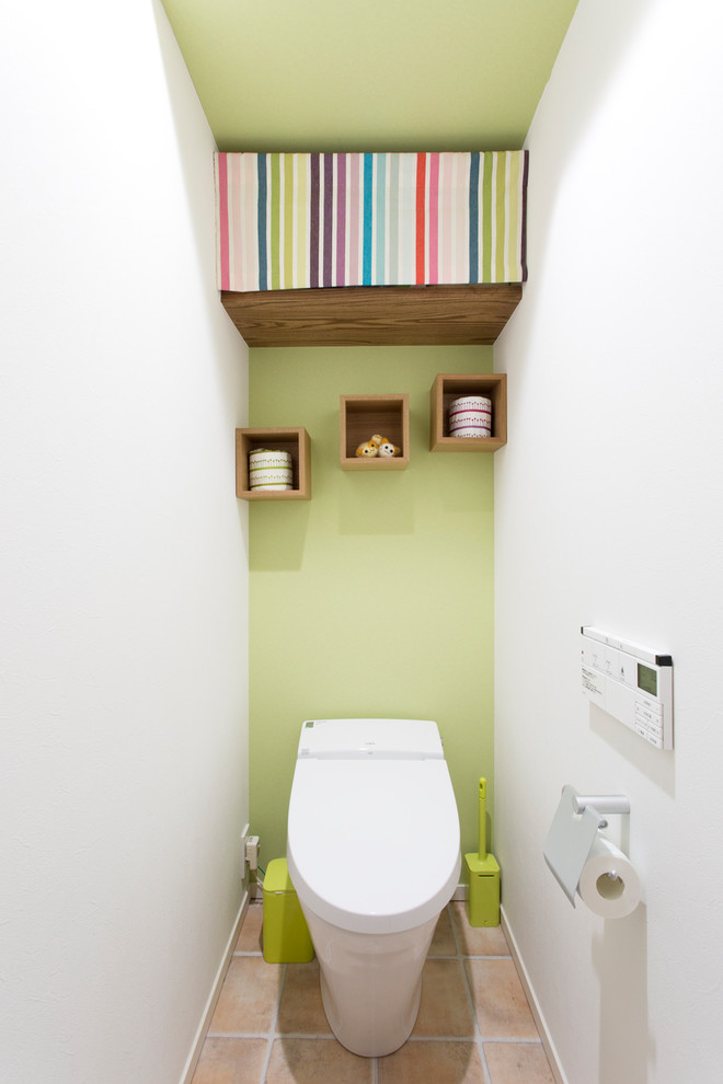 На фото: туалет в современном стиле с зелеными стенами, полом из терракотовой плитки и коричневым полом с
