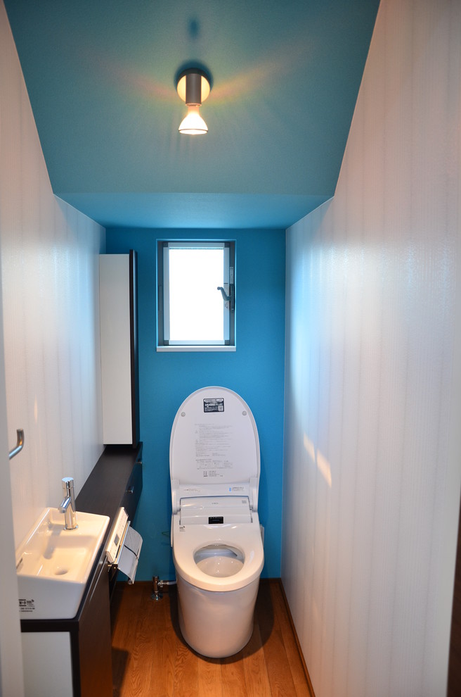 Inspiration för moderna toaletter, med en toalettstol med hel cisternkåpa, blå väggar, plywoodgolv och ett integrerad handfat