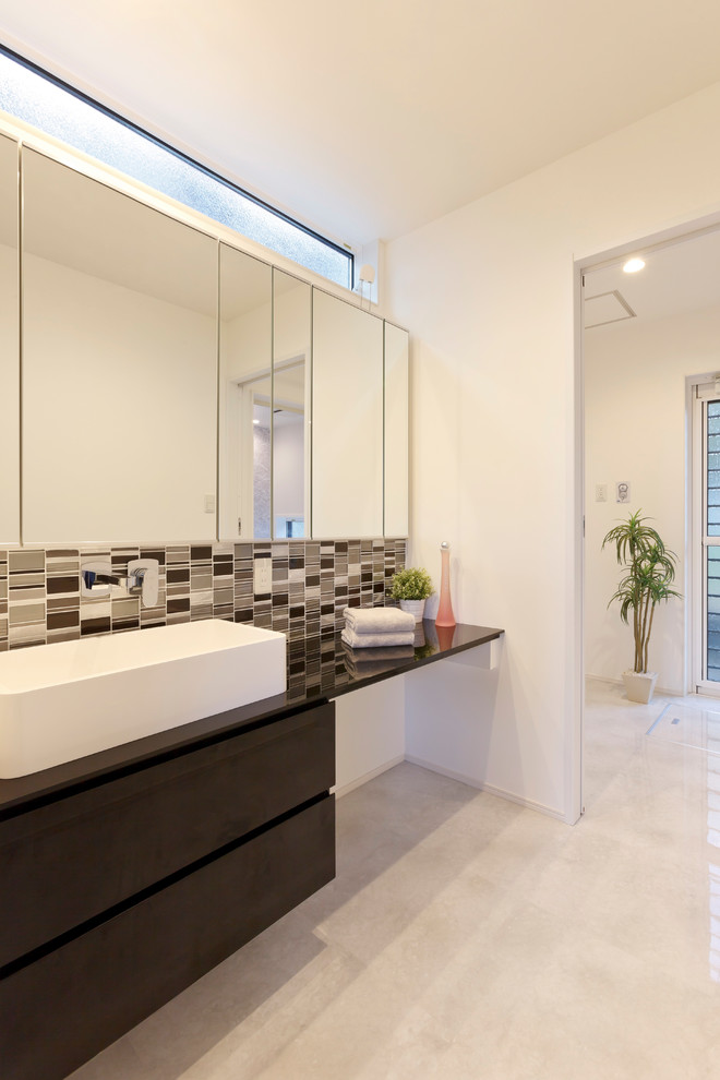 他の地域にあるモダンスタイルのおしゃれなトイレ・洗面所 (白い壁、ベージュの床、黒い洗面カウンター) の写真