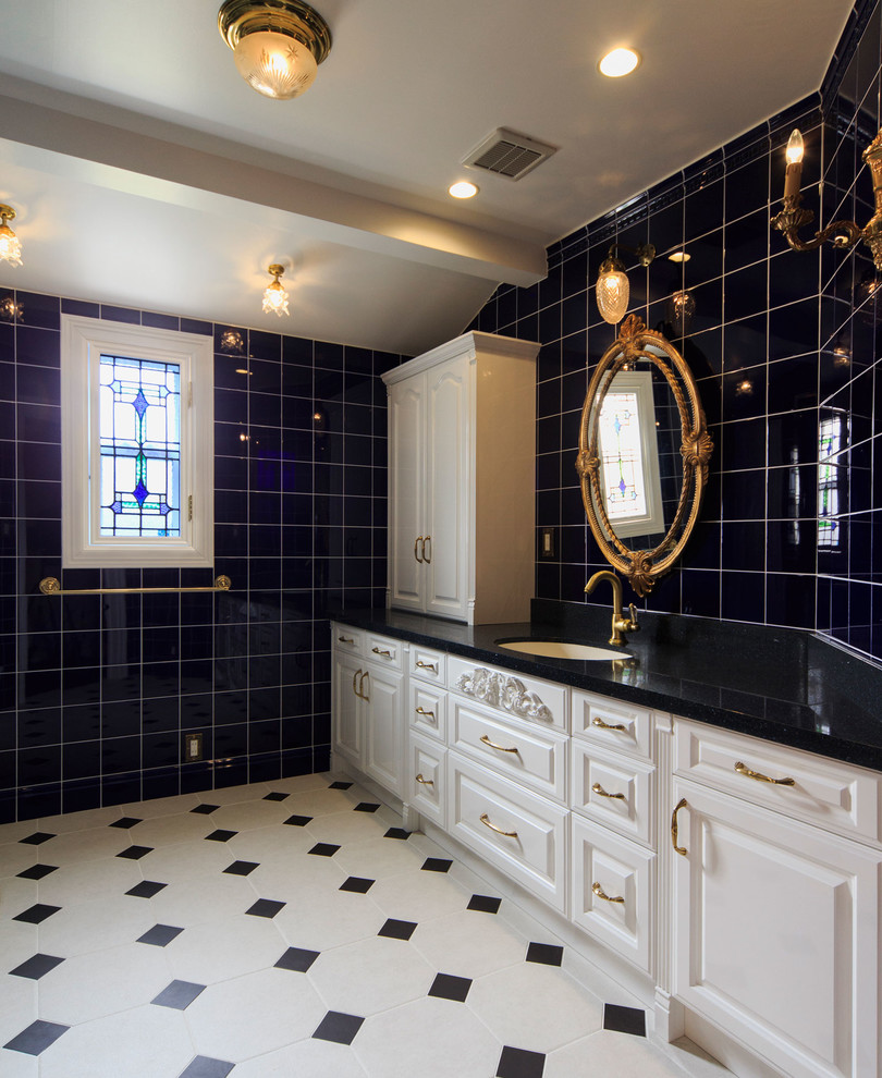 На фото: большой туалет в викторианском стиле с фасадами с выступающей филенкой, белыми фасадами, черной плиткой, стеклянной плиткой, черными стенами, полом из керамической плитки и врезной раковиной