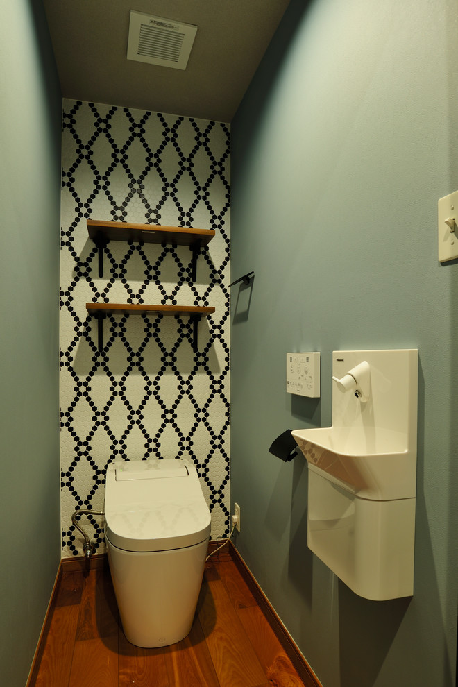 На фото: туалет в восточном стиле с подвесной раковиной, коричневым полом, черно-белой плиткой, зелеными стенами и темным паркетным полом с