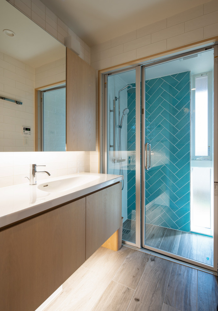 Cette image montre une salle de bain minimaliste en bois clair avec un placard à porte plane, un carrelage blanc, des carreaux de porcelaine, un mur blanc, un sol en carrelage imitation parquet, un lavabo intégré, un plan de toilette en quartz modifié, un sol gris, un plan de toilette bleu et meuble-lavabo encastré.