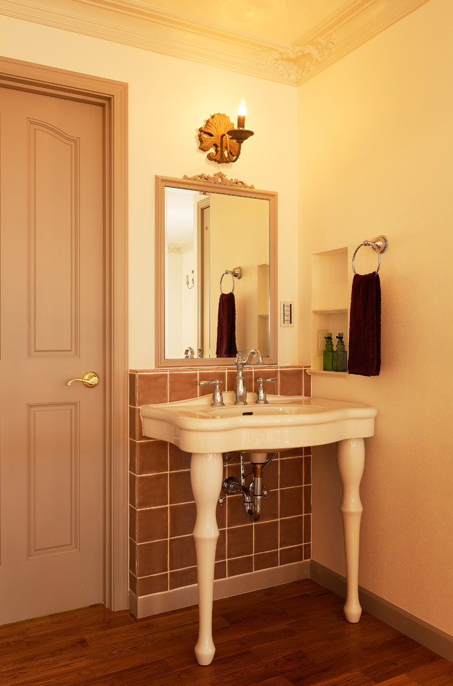 他の地域にあるトラディショナルスタイルのおしゃれなトイレ・洗面所 (白い壁、濃色無垢フローリング、コンソール型シンク、茶色い床) の写真